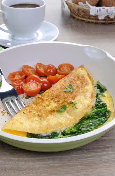 Omelet with spinach, cheese and roasted tomatoes in a pan
