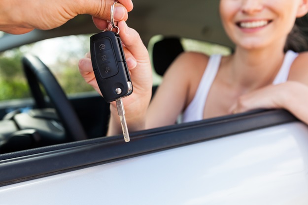 young smiling woman sitting in car taking key handover rent purchase