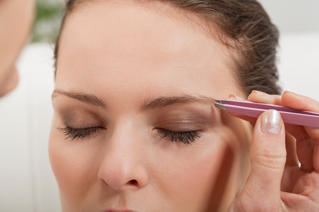 young beautiful woman eyebrow plucking tweezers eyes hair closeup portrait