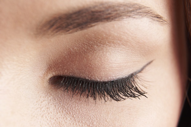 close up of womans brown eye lid with false eye lashes