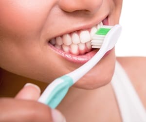 Smiling young woman with healthy teeth holding a tooth brush