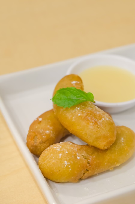 close up fried banana with vanilla sauce on white plate